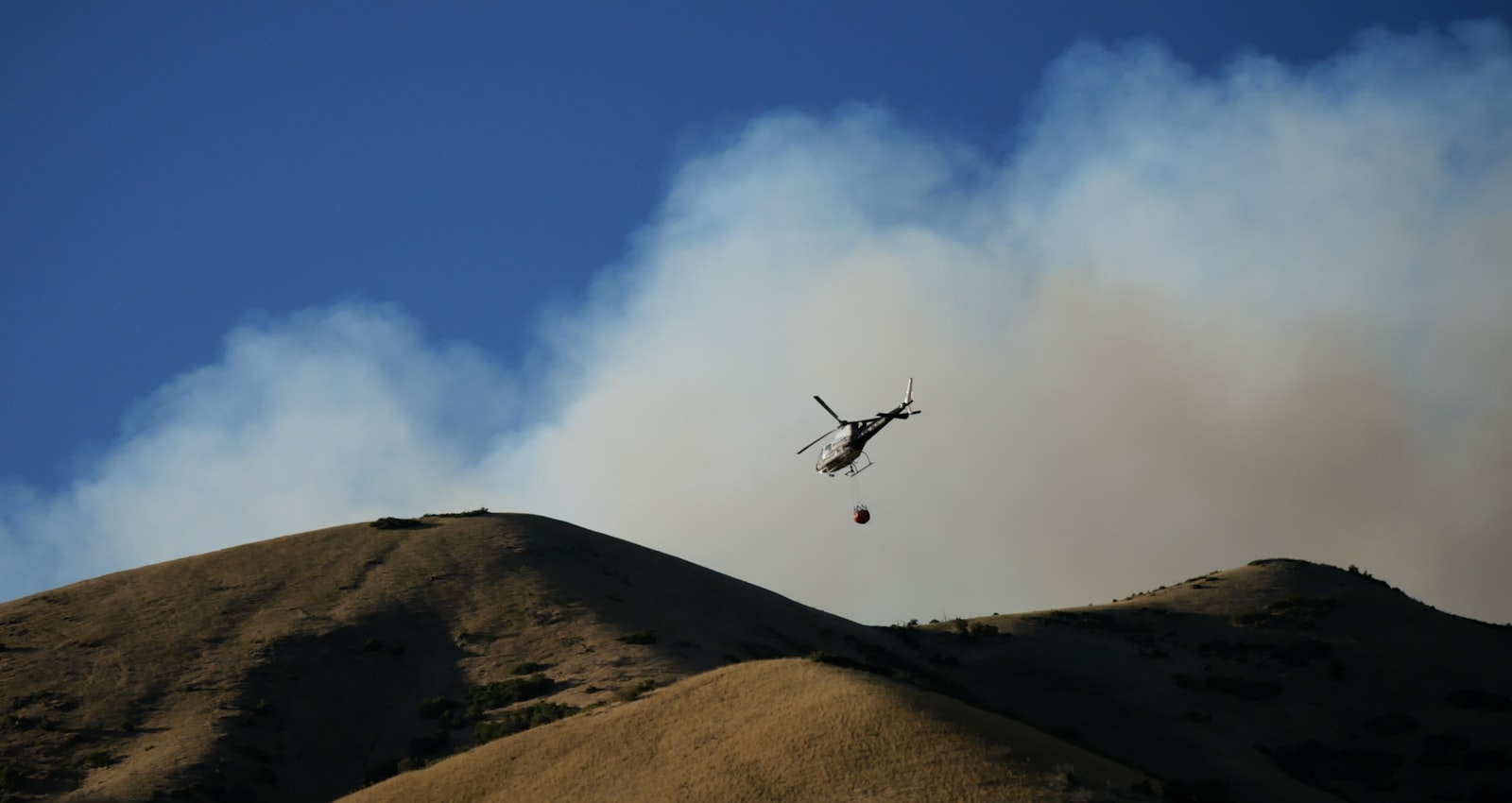 Helicóptero de extinción sobre un incendio en un entorno natural con humo